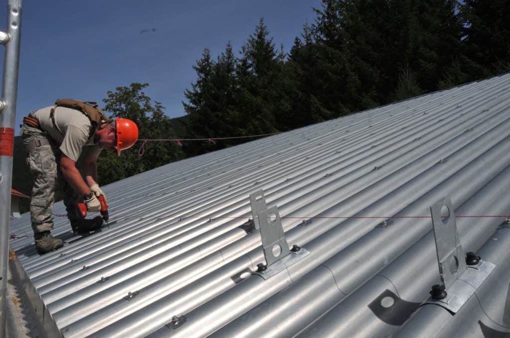 Metal Roof Cost In Minneapolis 2019 - Man Working on Metal Roof