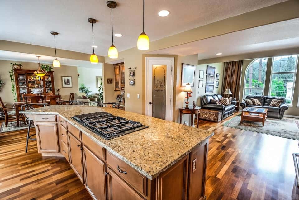 Worst Home Improvements for ROI - A Upscale Kitchen with an Island Stove and Brown and Tan Granite Countertops