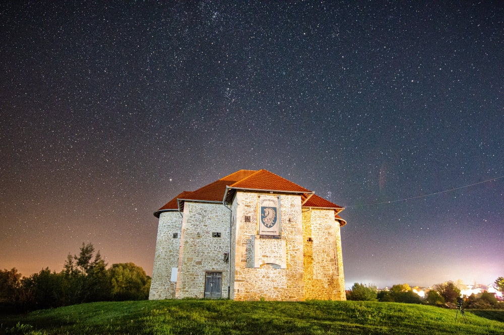 a stone house on a hill under the night sky