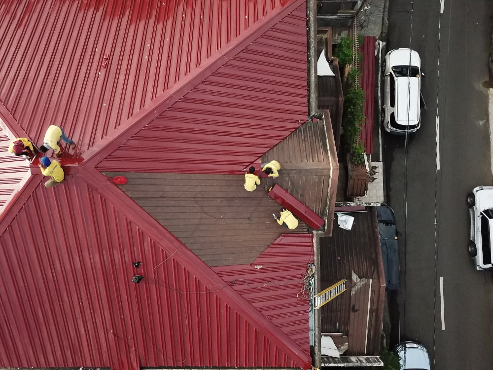 Six people repairing a red roof.