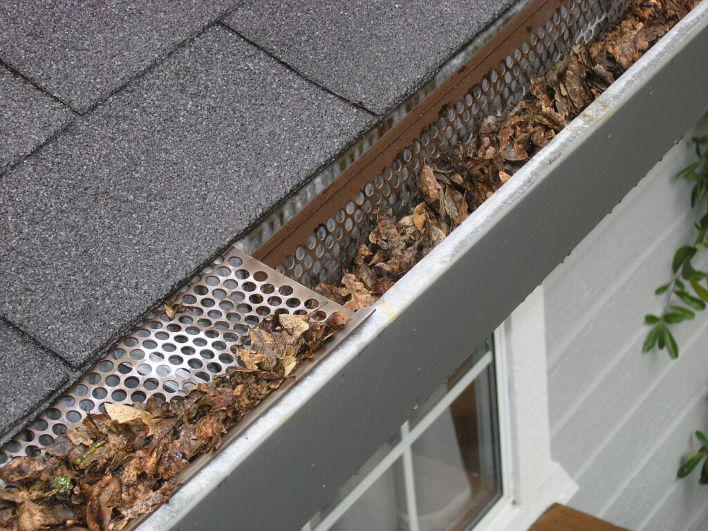 How Often Should Gutters be Cleaned? - Gutters on a House Full of Leaves and Debris