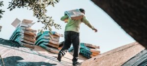 Construction worker carrying heavy shingles